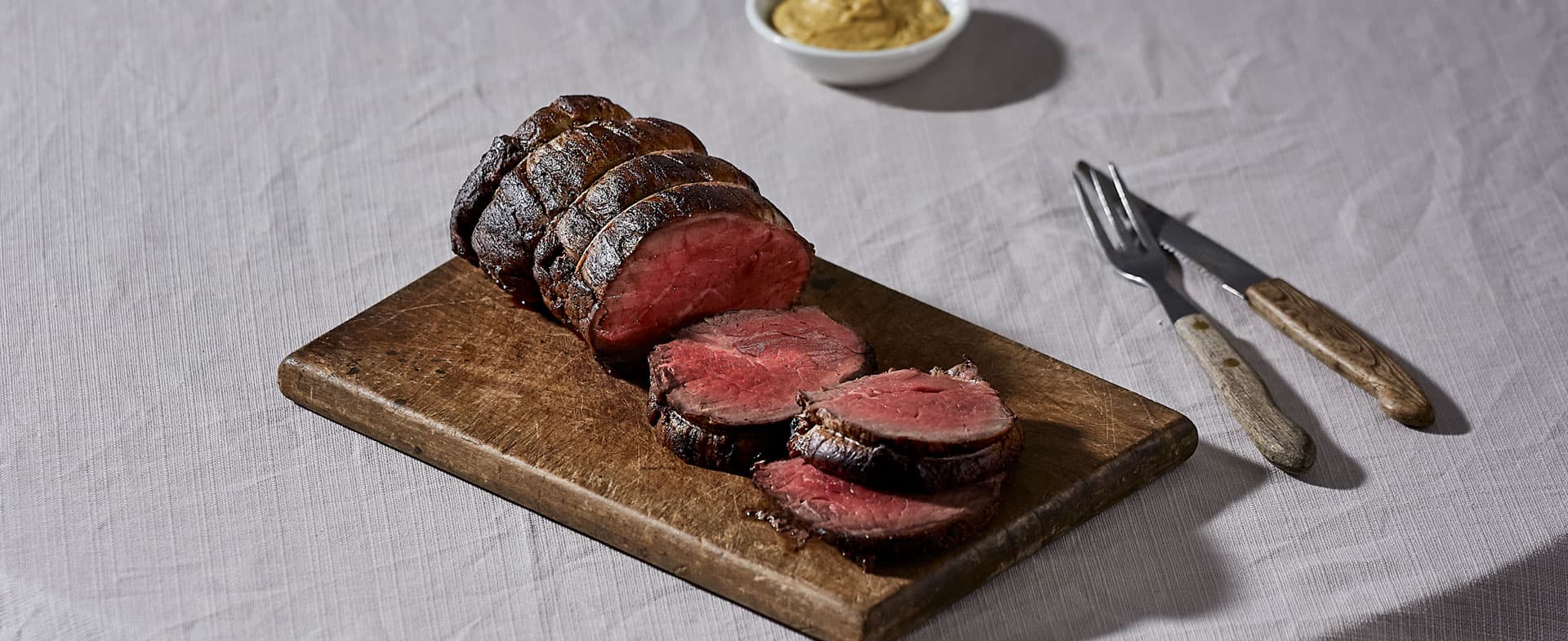 A joint of meat sliced on chopping board.