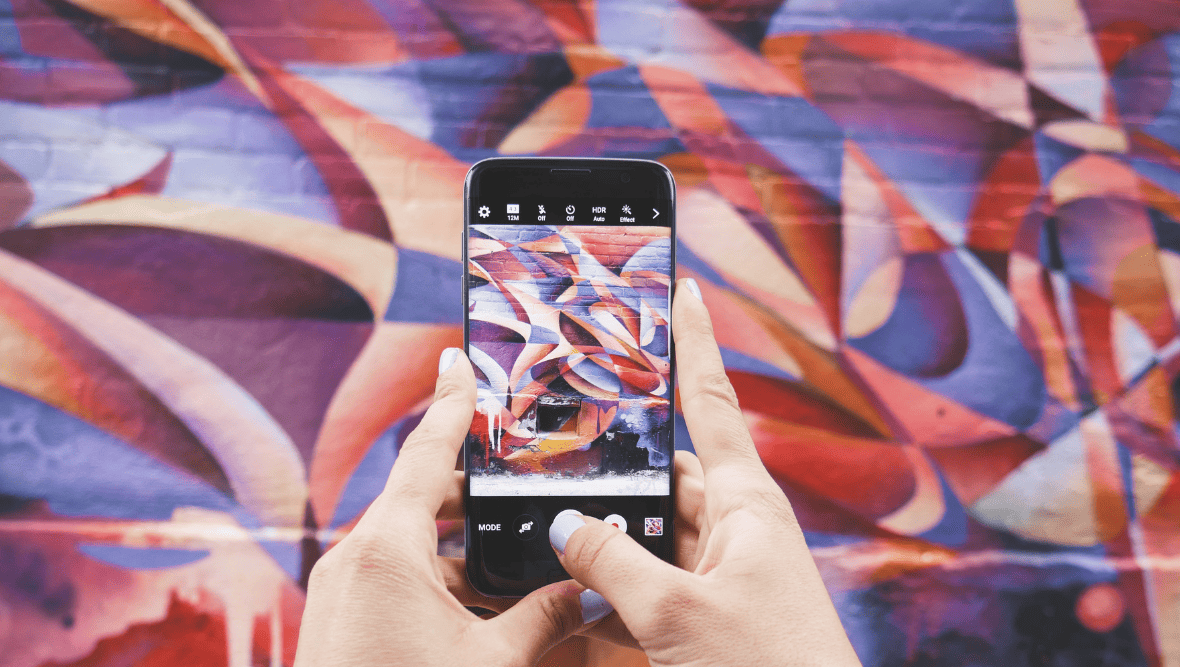 Mobile phone being held in front of wall mural.